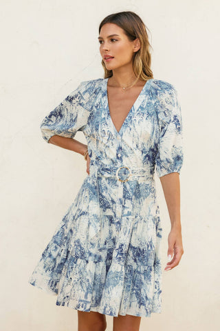 Woman wearing a blue and white patterned dress against a plain background