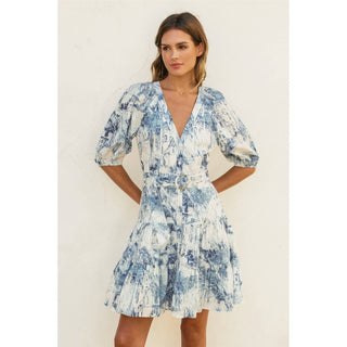 Woman wearing a blue and white patterned dress against a plain background
