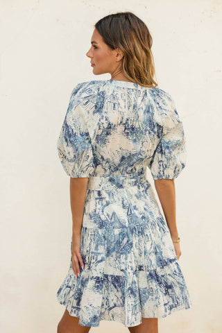 Woman wearing a blue and white floral dress against a plain background