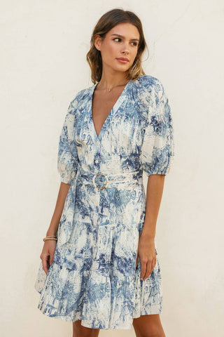 Woman wearing a blue and white patterned dress against a plain background
