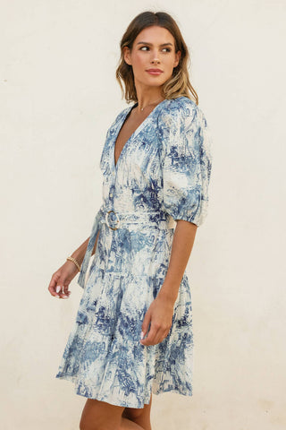 Woman wearing a blue and white patterned dress against a plain background
