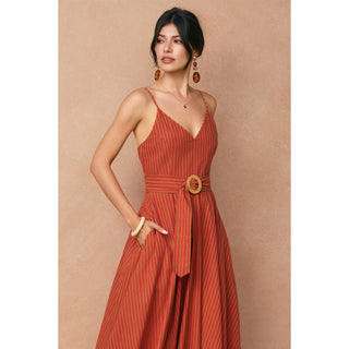 Woman wearing a red striped dress with a belt against a beige background