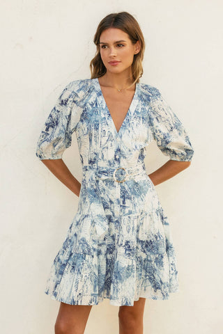 Woman wearing a blue and white patterned dress against a white background